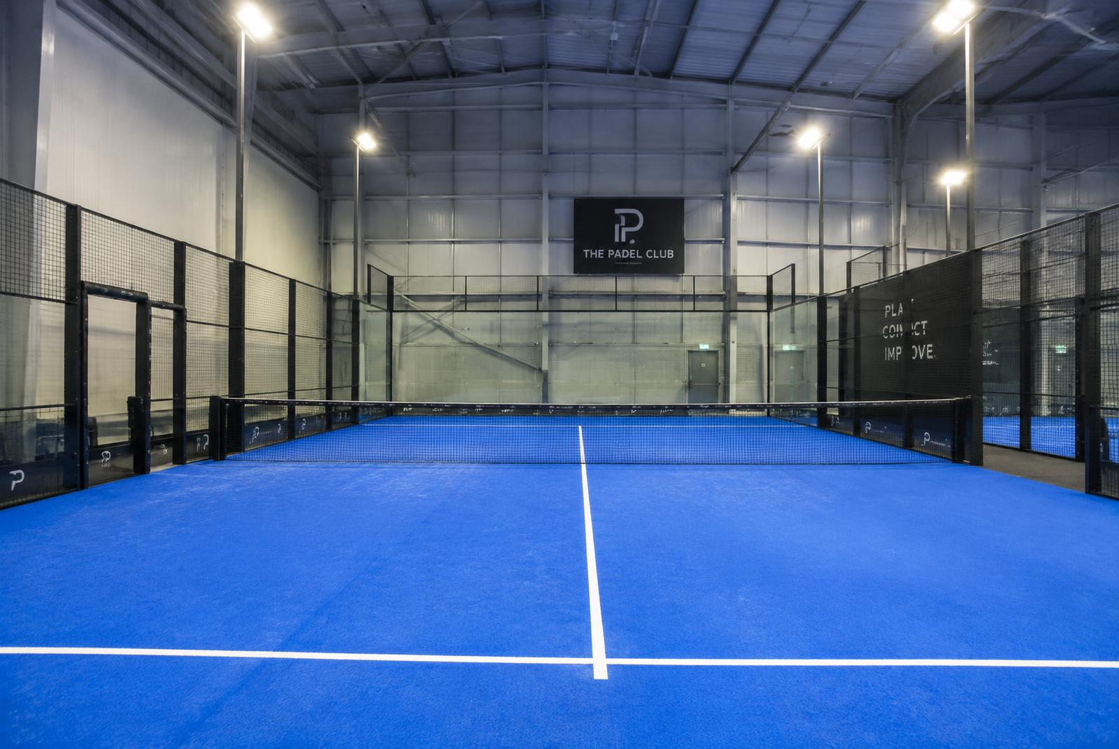 Indoor padel court inside a clear-span building with roof lighting